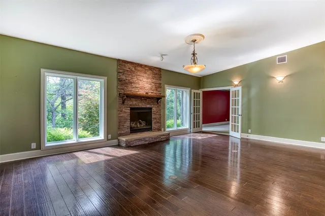 a view of an empty room with wooden floor fireplace and a window