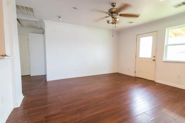 an empty room with wooden floor and windows