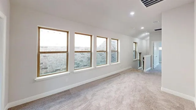 an empty room with windows and chandelier fan