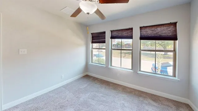 an empty room with chandelier fan and windows