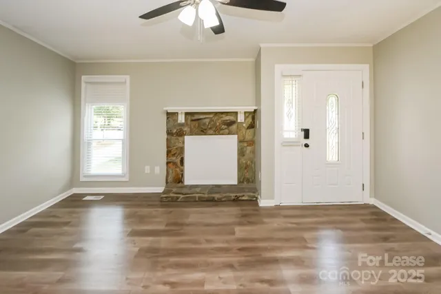 a view of an empty room with window and wooden floor