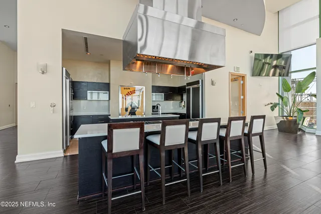 a kitchen with stainless steel appliances kitchen island granite countertop a table chairs and a refrigerator