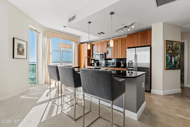 a kitchen with stainless steel appliances granite countertop a table chairs and a refrigerator