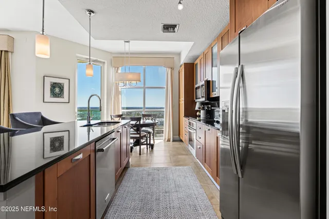 a kitchen with stainless steel appliances granite countertop a refrigerator a stove and a sink