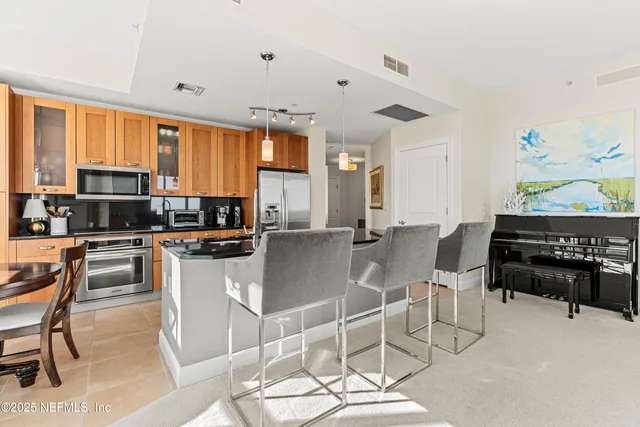 a kitchen with stainless steel appliances kitchen island granite countertop a stove a sink a dining table and chairs