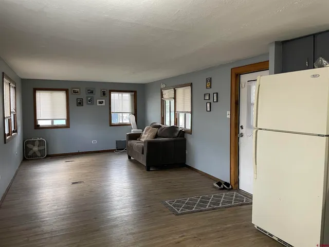 a living room with furniture and a refrigerator