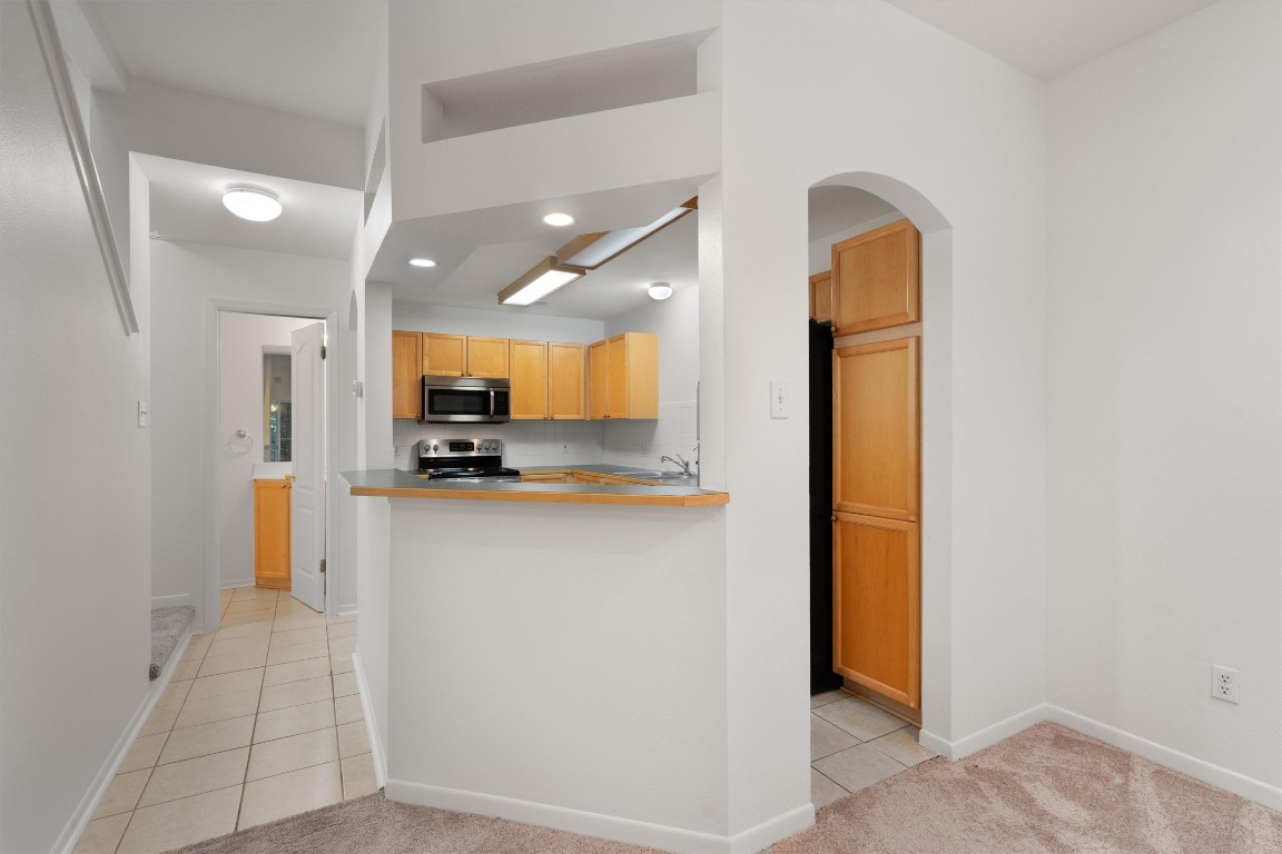 a view of kitchen with stainless steel appliances granite countertop cabinets and empty room