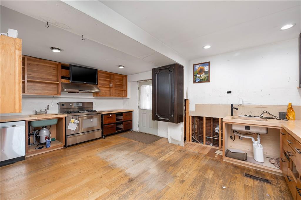 438 Main Street Prospect, PA 16052 - Photo 13 of 46 a large kitchen with stainless steel appliances granite countertop a large stove a sink dishwasher and white cabinets with wooden floor