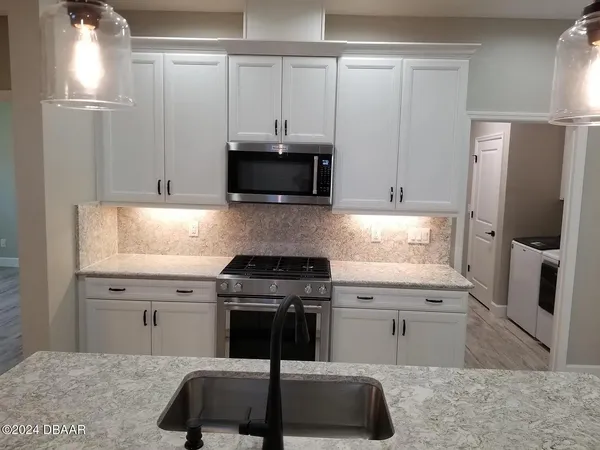 a kitchen with stainless steel appliances white cabinets and a stove top oven