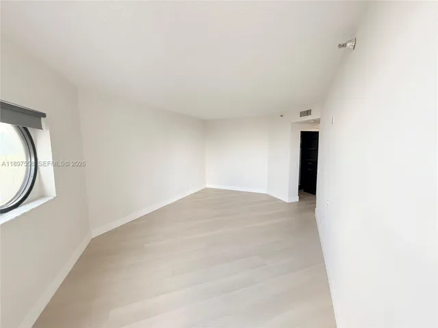 a view of an empty room with wooden floor and closet