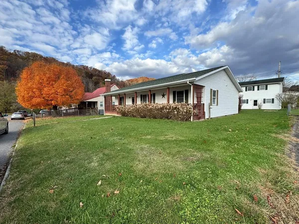 a view of house with a big yard and large trees