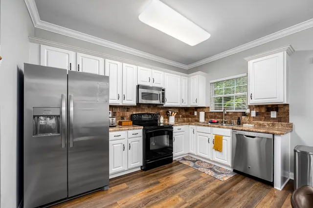 a kitchen with stainless steel appliances granite countertop a refrigerator a stove top oven a sink and dishwasher with wooden floor