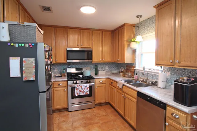 a kitchen with stainless steel appliances granite countertop a stove a sink dishwasher and a microwave oven with cabinets