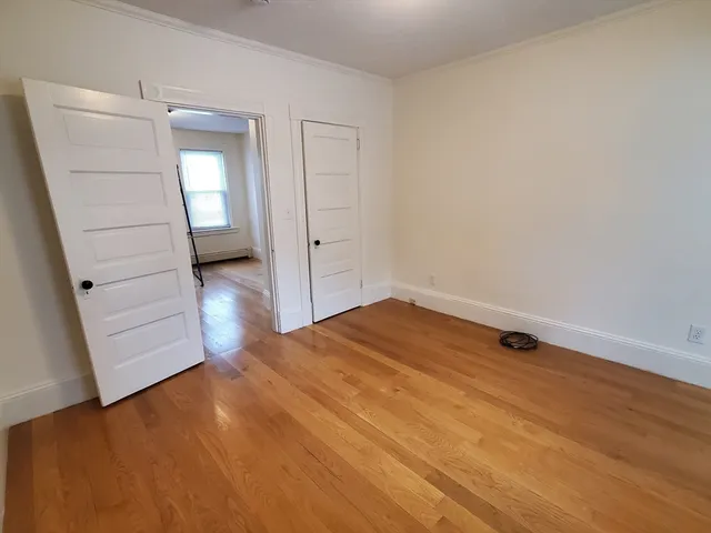 an empty room with wooden floor cabinet and closet