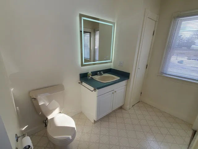 a bathroom with a granite countertop toilet and a sink