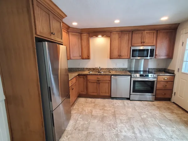 a kitchen with granite countertop stainless steel appliances and refrigerator