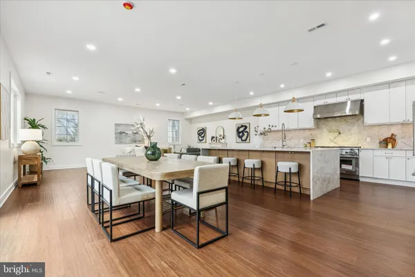 a large kitchen with stainless steel appliances refrigerator a dining table and chairs