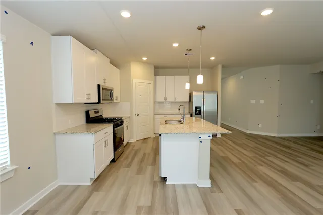 a large kitchen with stainless steel appliances kitchen island a large counter top a sink a stove and a refrigerator