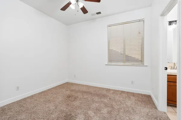 an empty room with a window and a fan