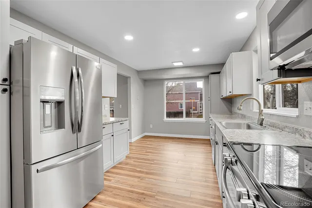 a kitchen with stainless steel appliances granite countertop a refrigerator a sink dishwasher a stove and a refrigerator