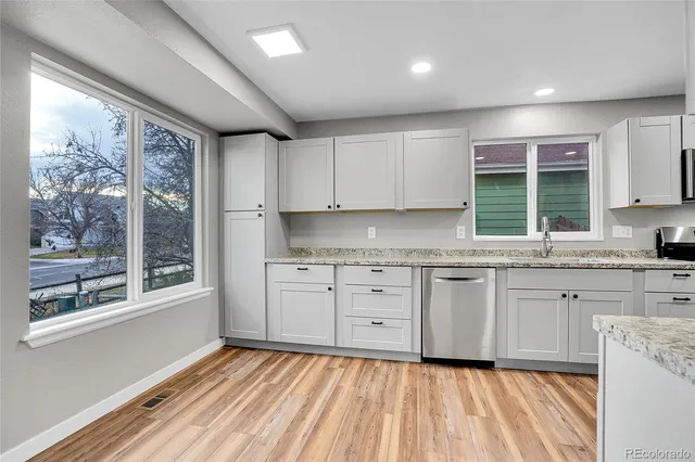 a kitchen with granite countertop cabinets stainless steel appliances and a large window