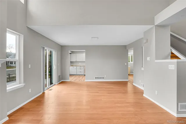 a view of an empty room with window and wooden floor
