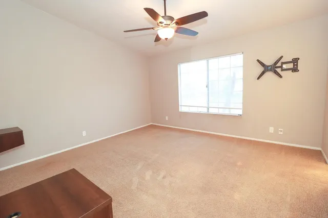 an empty room with windows and fan