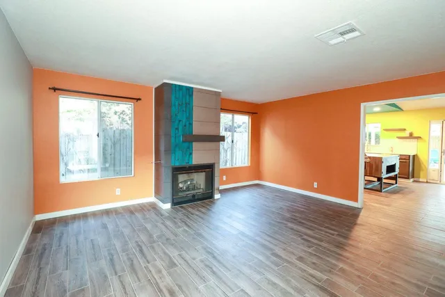 an empty room with wooden floor and windows