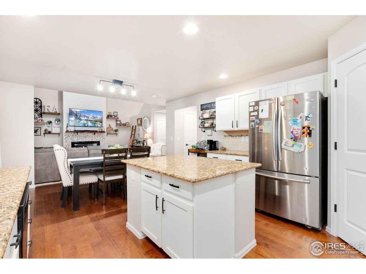 7334 23rd St Road Greeley, CO 80634 - Photo 11 of 31 a kitchen with stainless steel appliances kitchen island granite countertop a refrigerator a stove a sink dishwasher and white cabinets with wooden floor