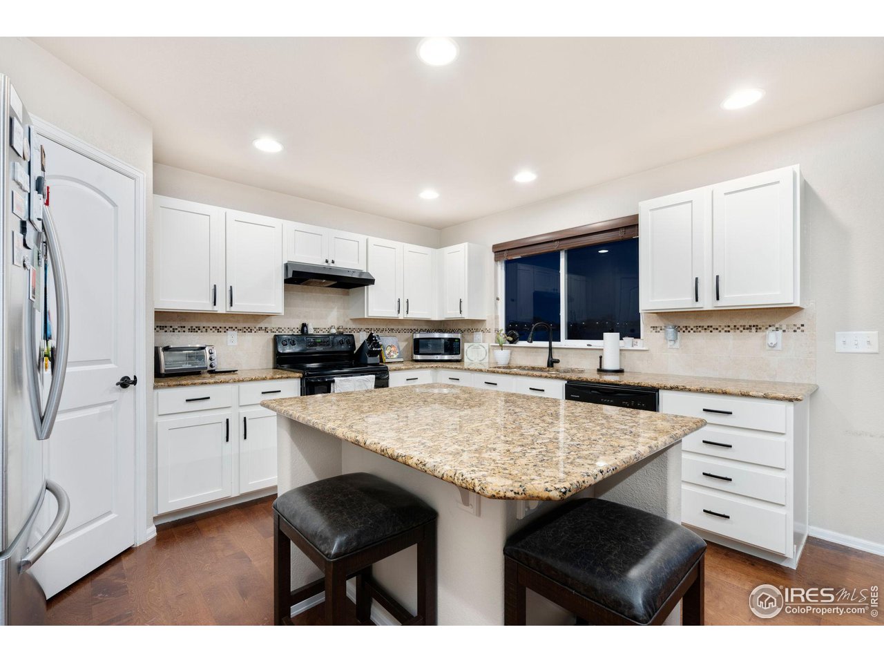 7334 23rd St Road Greeley, CO 80634 - Photo 10 of 31 a kitchen with granite countertop a sink stove cabinets and refrigerator