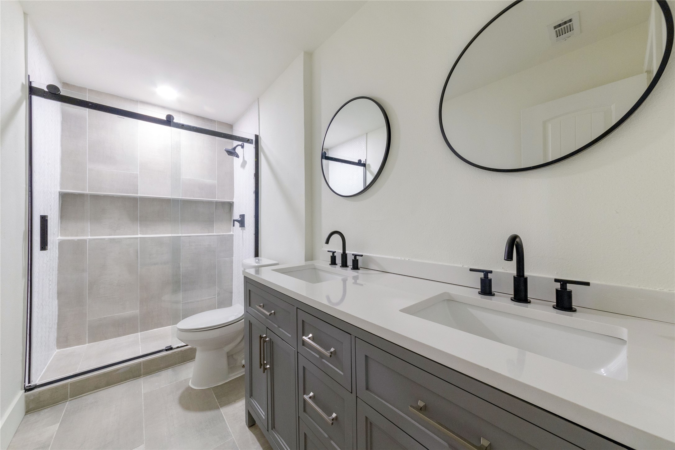 8807 Merion Circle Austin, TX 78754 - Photo 13 of 18 A well-appointed bathroom with a dual vanity, sleek fixtures, and a glass-enclosed shower.