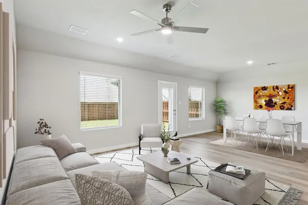 an empty room with wooden floor fan and windows
