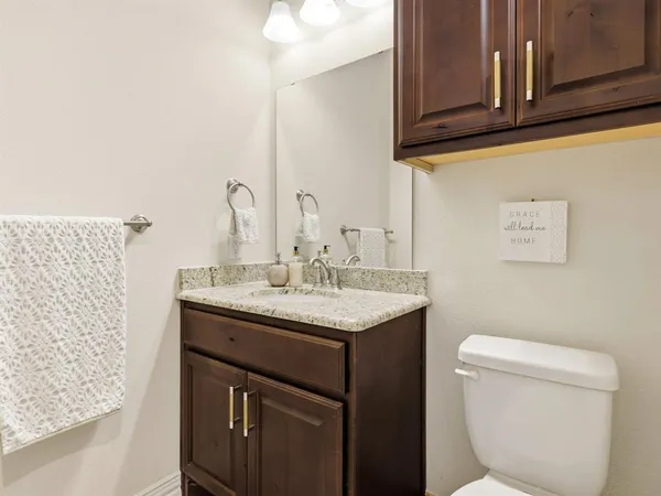 a bathroom with a granite countertop toilet sink and mirror