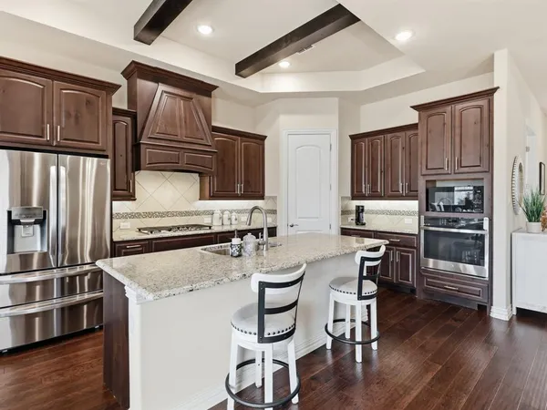 a kitchen with granite countertop a refrigerator stove and microwave