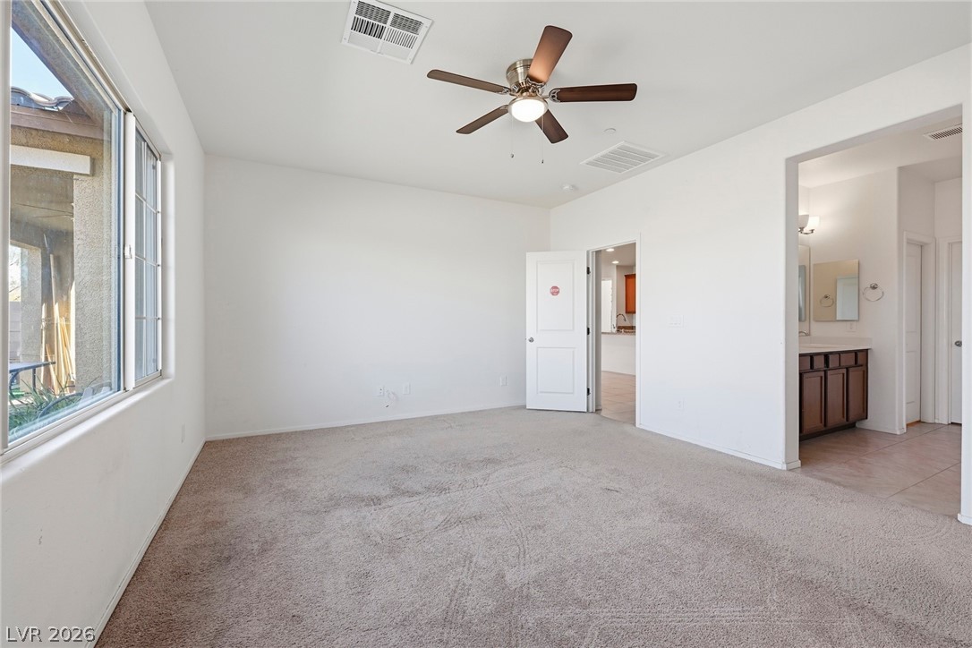 250 Dedication Avenue Henderson, NV 89011 - Photo 22 of 67 Unfurnished bedroom featuring light carpet, ceiling fan, and ensuite bathroom