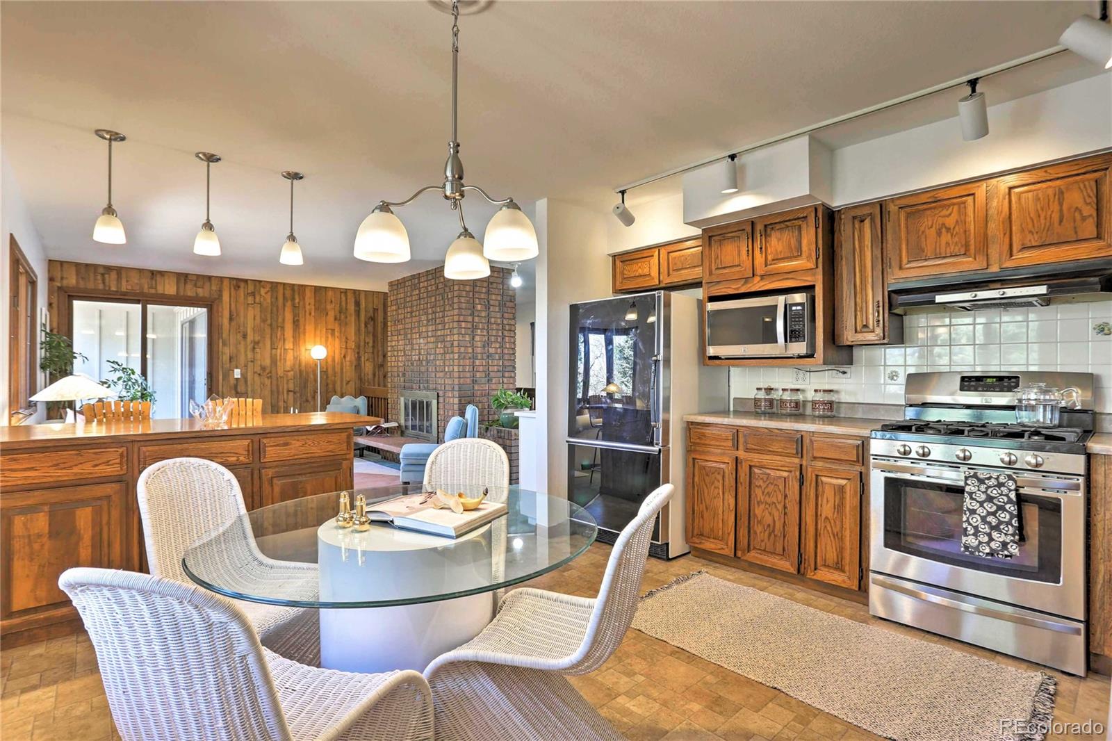 4452 South Xeric Way Denver, CO 80237 - Photo 12 of 40 a kitchen with stainless steel appliances granite countertop a stove a sink dishwasher a dining table and chairs with wooden floor