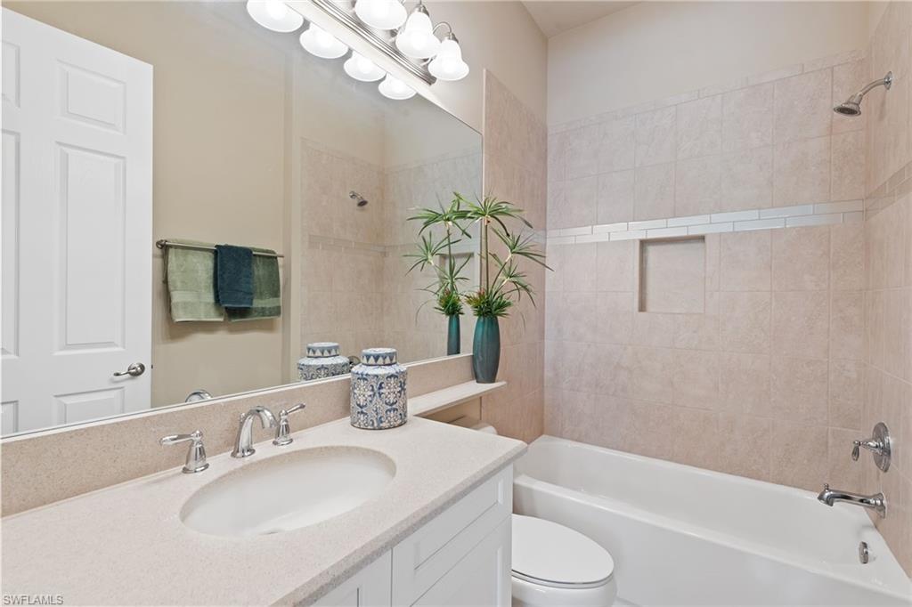 13338 Coronado Drive Naples, FL 34109 - Photo 9 of 22 a bathroom with a granite countertop sink toilet a large mirror a bathtub and shower