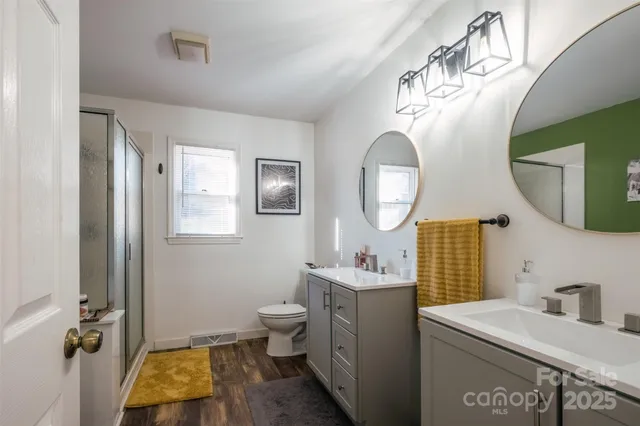 a bathroom with a toilet a sink a mirror and a window