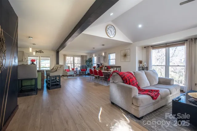 a living room with furniture kitchen view and a wooden floor