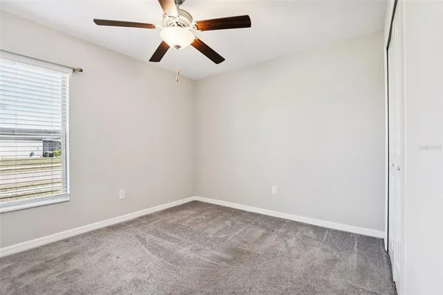 an empty room with a window and a fan