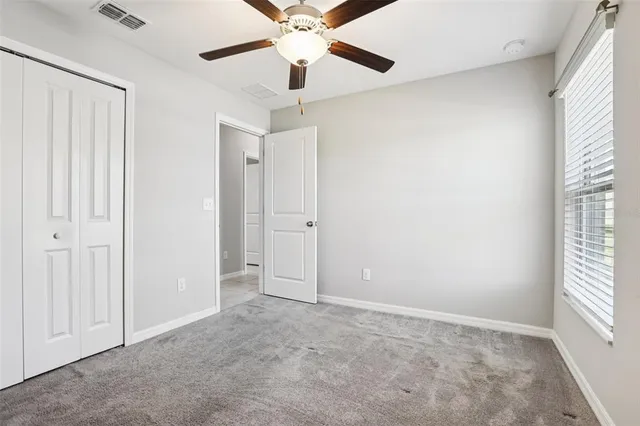 an empty room with a ceiling fan and a window