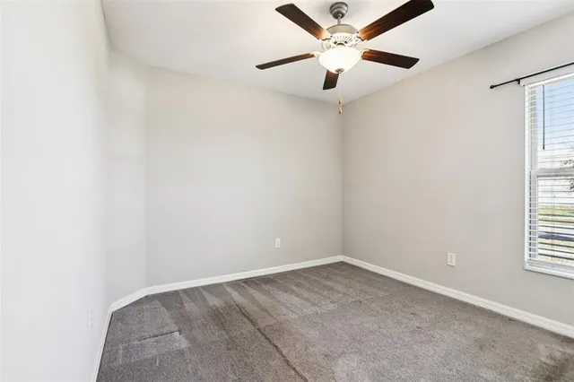 an empty room with a window and a fan