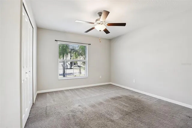 an empty room with a window and a fan
