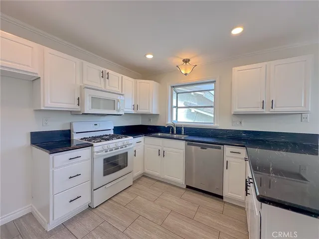 a kitchen with granite countertop white cabinets and white appliances