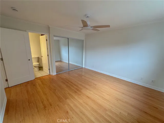 an empty room with wooden floor and fan