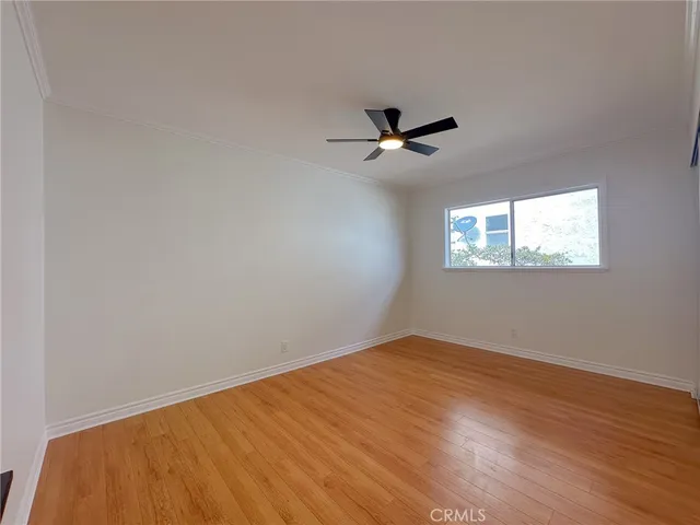 a view of empty room with wooden floor and fan