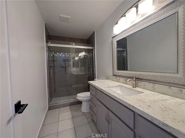 a bathroom with a granite countertop sink a toilet and shower