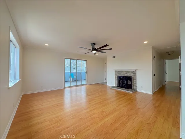 an empty room with wooden floor fireplace and windows
