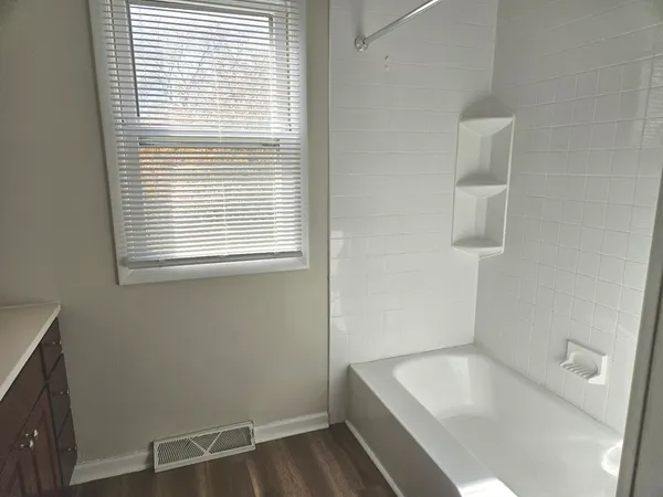 a bathroom with a tub a sink and a window