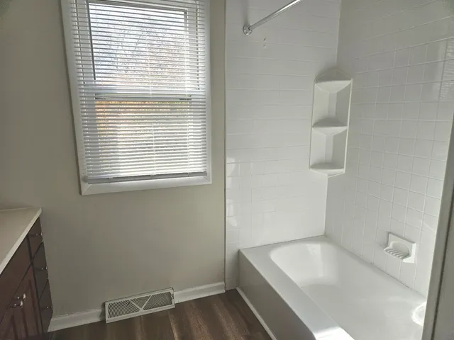 a bathroom with a tub a sink and a window